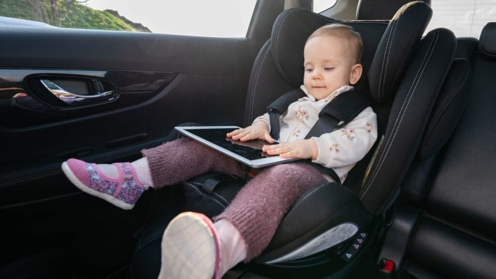 Baby-using-digital-tablet-while-sitting-in-car-seat.-Concept-of-technology-use-for-kids-on-road