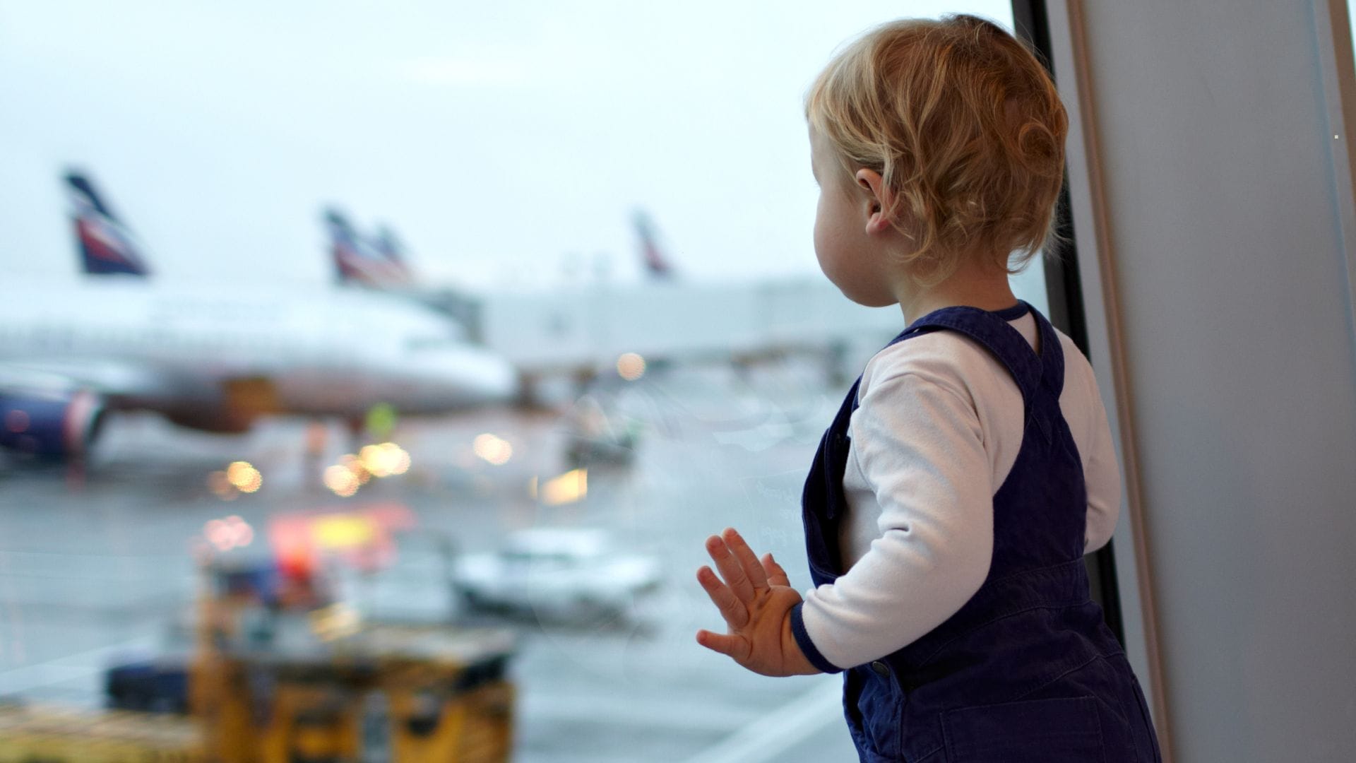cute-toddler-looking-at-airline-through-the-window